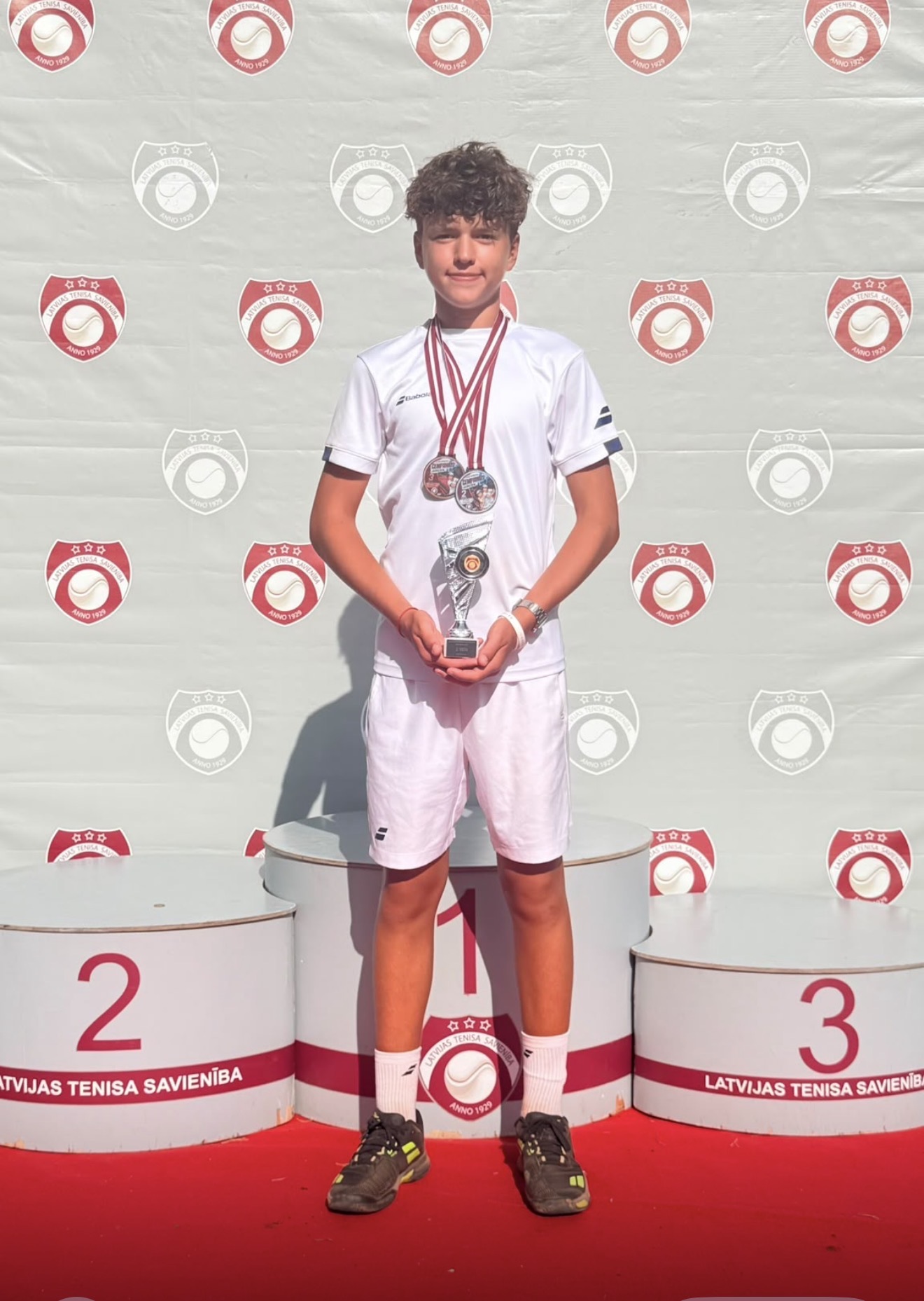 First season participant on a tennis podium with medals and a trophy
